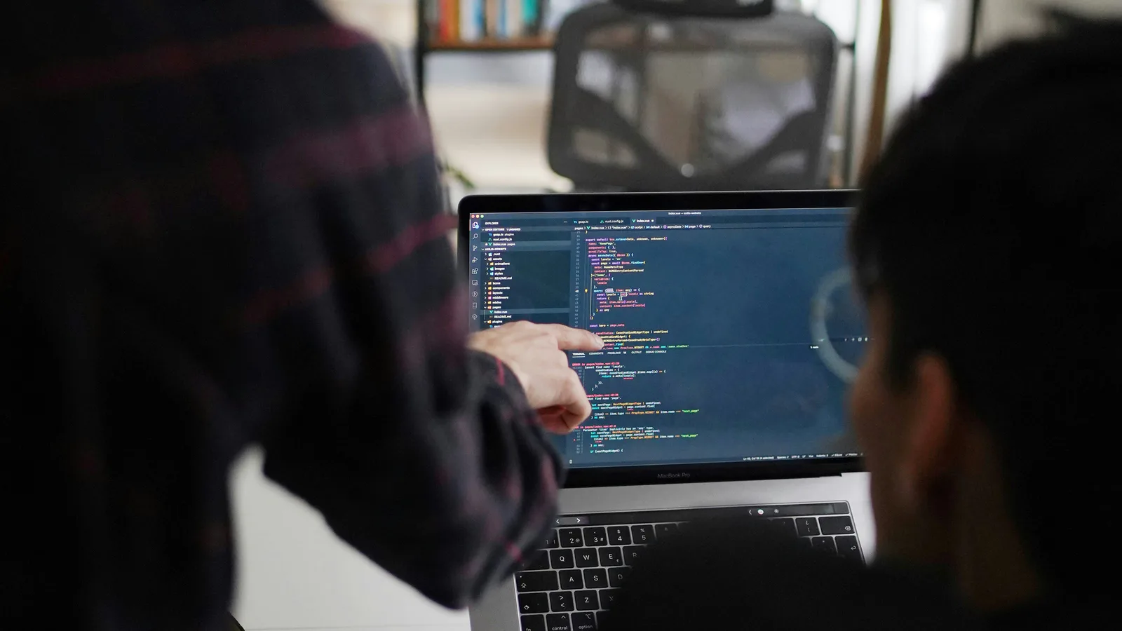Two people reviewing inherited application code on a laptop